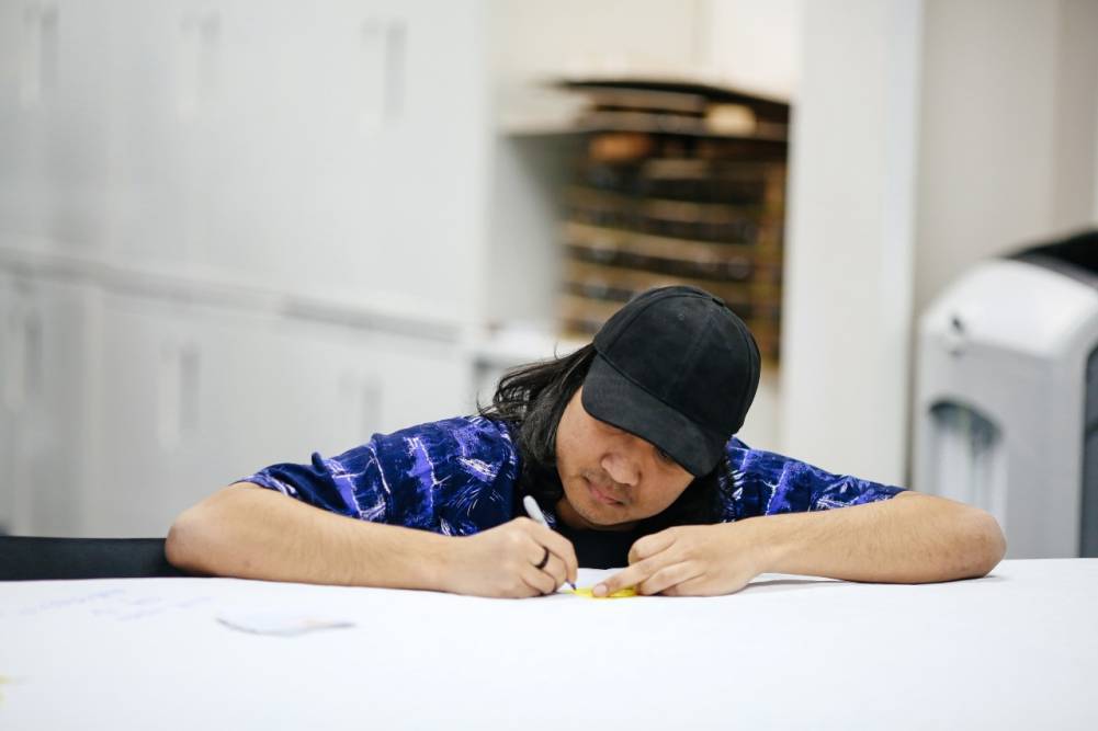 Male student leaning on desk drawing 