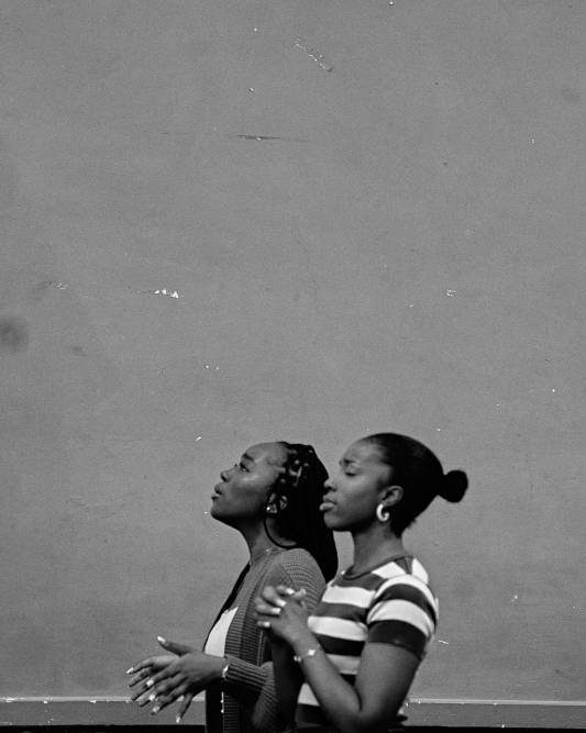 Two women stand with their hands in prayer