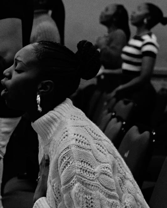 Black and white photograph shows women standing and singing in prayer