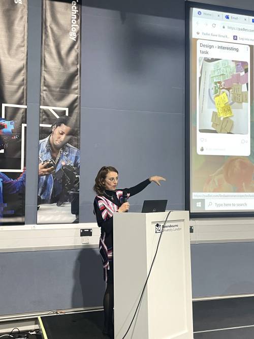 Virna Rossi holds a microphone as she presents from a podium